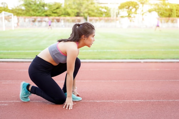 Young female acting ready to run at the football stadium in the morning