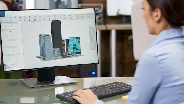 Young female architect working on computer with 3d building models. Architect working with modern technology.