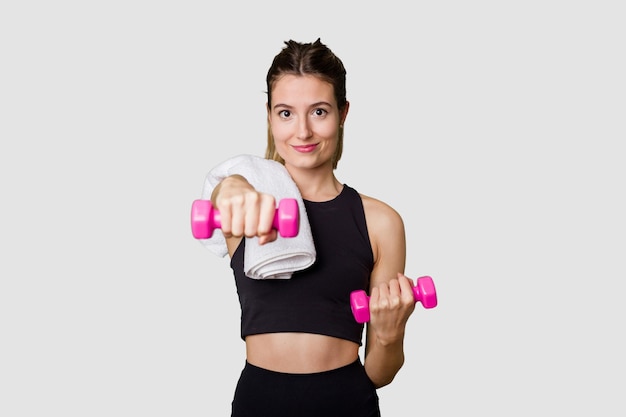 Young female athlete lifting weights focused and determined in indoor studio