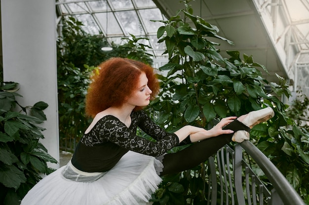 Young female ballerina dancing in an indoors botanical garden