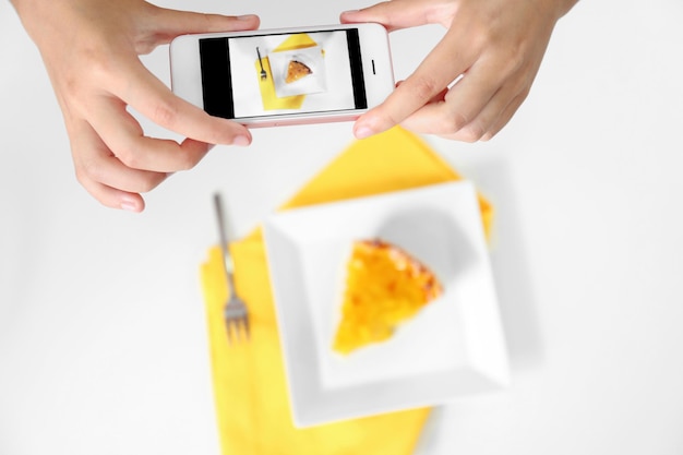 Young female blogger taking photo of dish on table