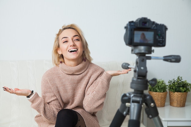 Young female blogger next to video camera at home