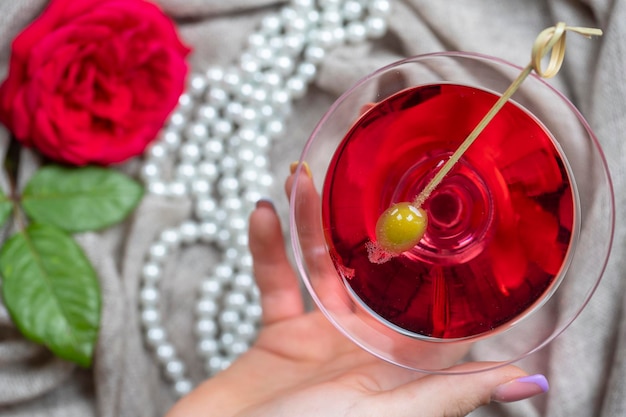 Young female caucasian hand holding a martini with olives closeup top view