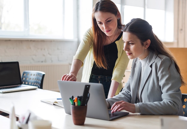 Young female colleagues working on laptop in office