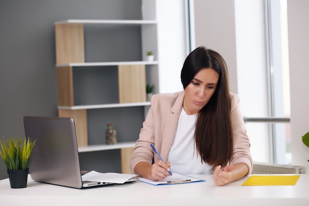 Young female content manager makes notes with a pen