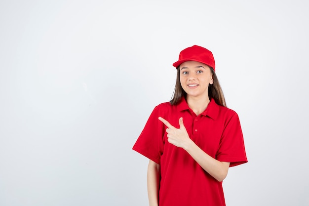 young female courier in red uniform pointing. 