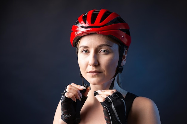 A young female cyclist wearing a safety helmet and glasses dressed in a bib shorts poses