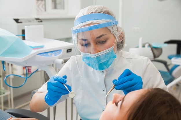 Young female dentist curing patient's teeth filling cavity