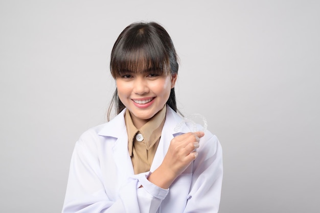 A young female dentist holding invisalign braces over white background studio, dental healthcare and Orthodontic concept.