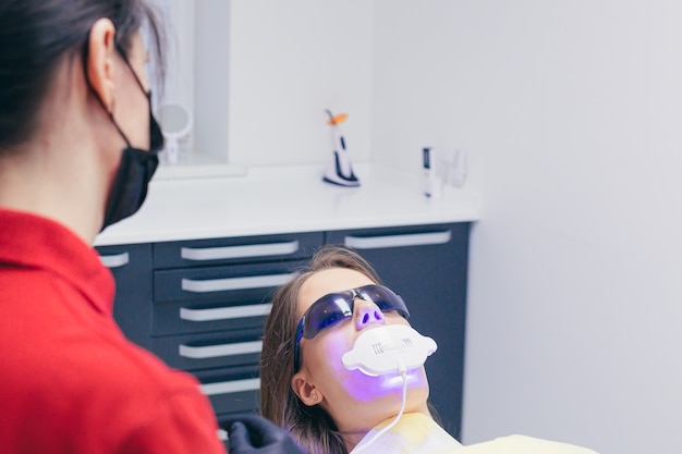 A young female dentist talks to a patient before starting treatment or a procedure at a modern dental clinic