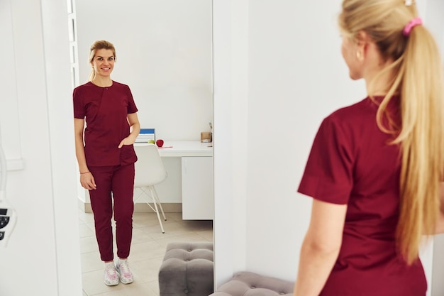 Young female dentist in uniform standing in stomatology office