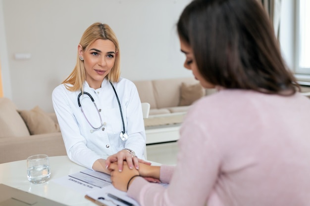 Young female doctor hold hand of woman patient give comfort express health care sympathy medical help trust support encourage reassure infertile patient at medical visit closeup view