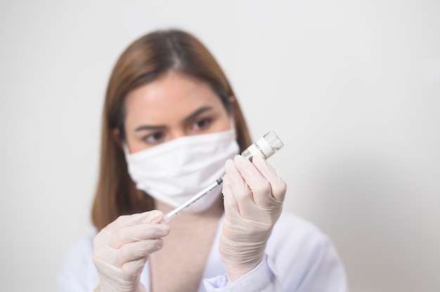 A young female doctor holding a syringe with covid-19 vaccine bottle for injection, covid-19 vaccination and health care concept