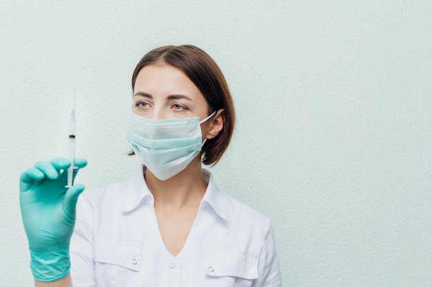 Young female doctor holds a syringe in her hand and looks at it. Antibiotics concept