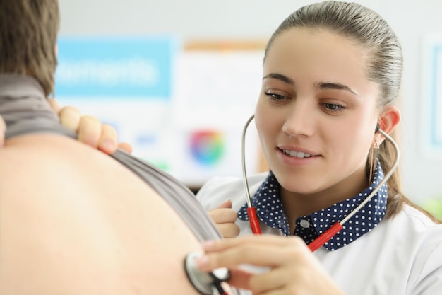 Young female doctor listen to patients back with stethoscope equipment