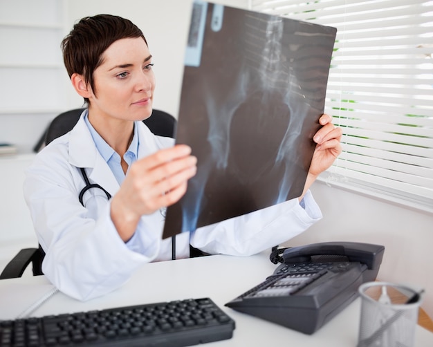 Young female doctor looking at X-ray