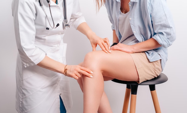 Young female doctor making an examination of patient and doing physical exercises Orthopedist