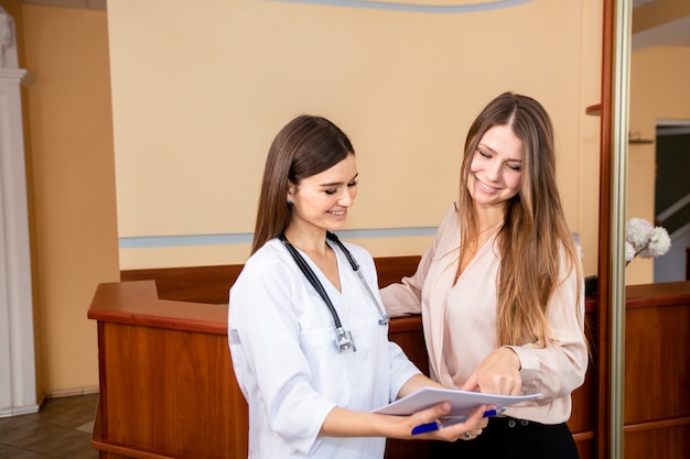 Young female doctor meets with the client at reception.