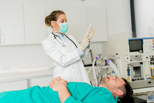 Young female doctor preparing syringe for male patient in the hospital