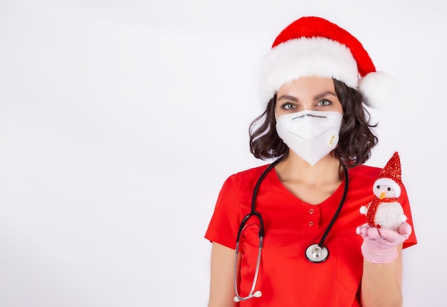 A young female doctor in a Santa hat holds a Snowman toy in her hand