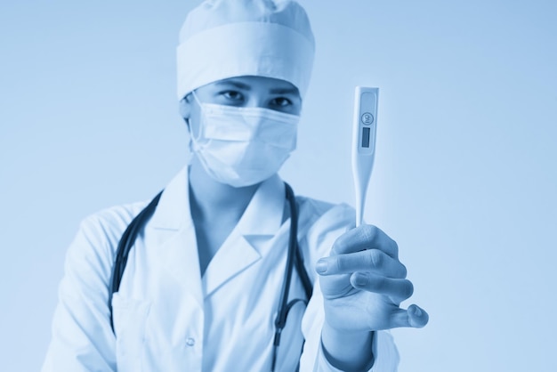 Young female doctor showing thermometer over white background studio shot