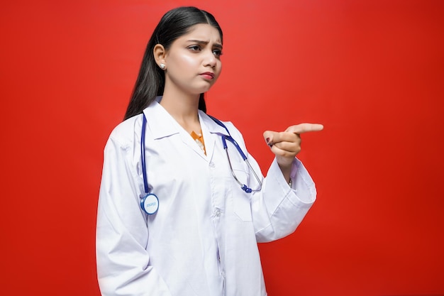 young female doctor wearing coat and stethoscope pointing finger right indian pakistani model