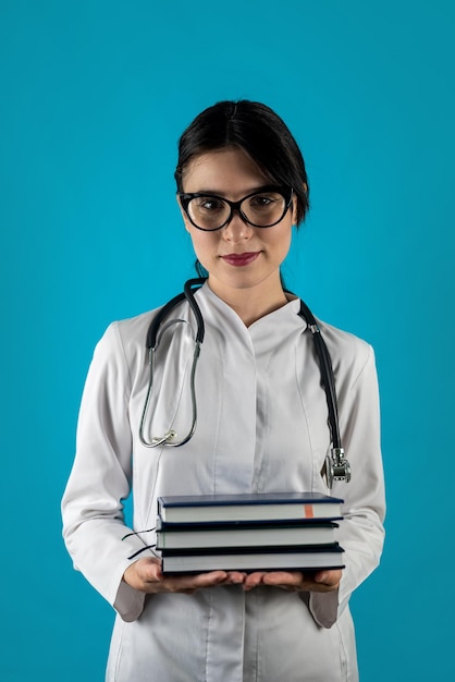 A young female doctor with a big toothy smile is holding a book portrait of isolated nurse in white uniform