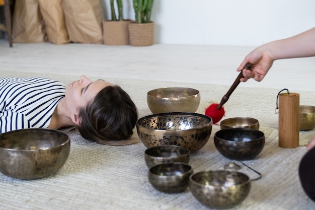 Photo young female doing tibetan massage therapy with singing bowls wellness meditation and wellbeing