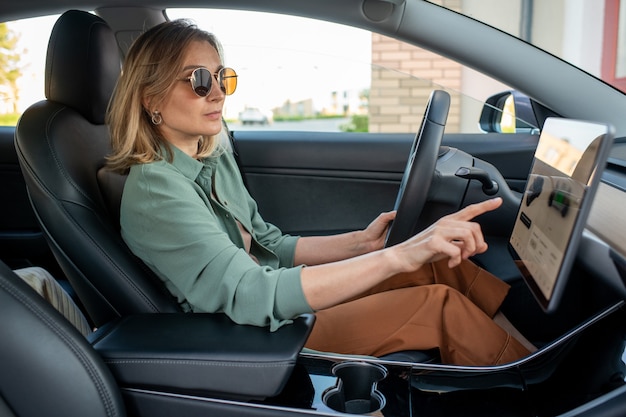 Young female driver pointing at display while choosing destination place