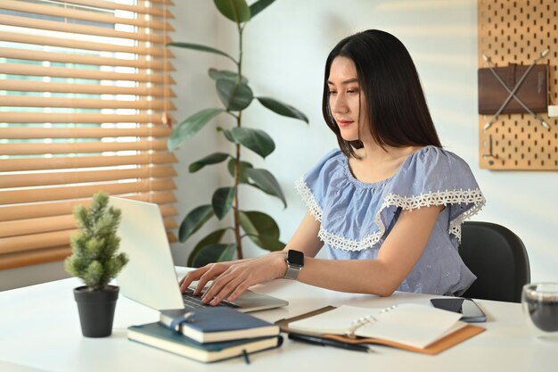 Young female entrepreneur chatting with client online on laptop computer working on online marketing at home office