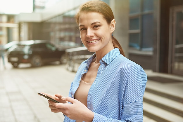 Young female entrepreneur using online banking for transferring money distantly via smartphone. Confident businesswoman texting email letter on cellphone using internet.