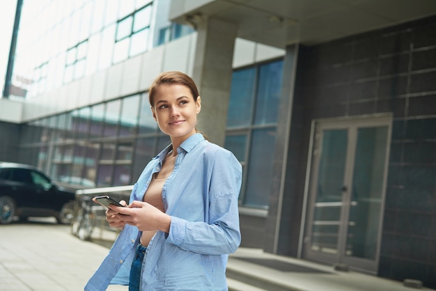 young female entrepreneur using online banking for transferring money distantly via smartphone 