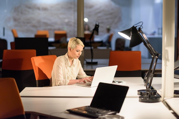 young female entrepreneur working on laptop computer in late night startup office