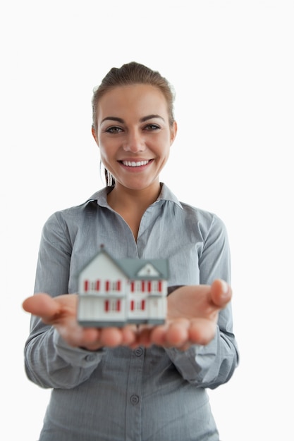 Photo young female estate agent presenting miniature house