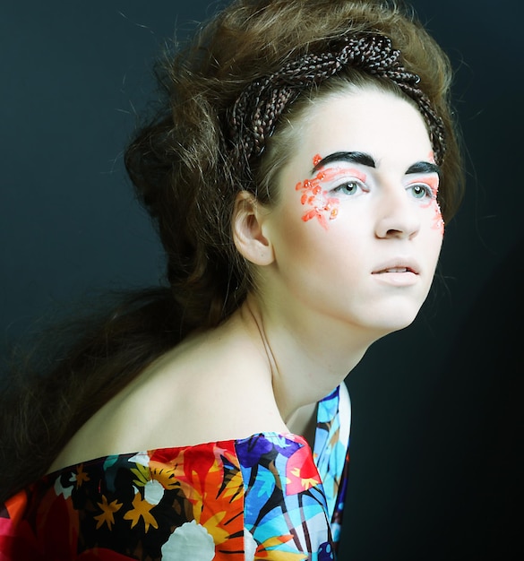 Young female face with bright fashion multicolored makeup