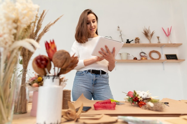 Young female florist reading from a clipboard