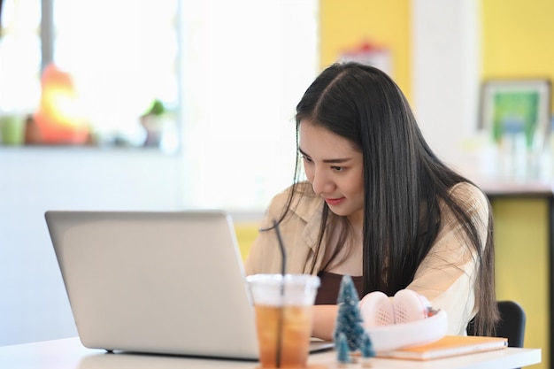 Young female freelancer sitting at her workplace and concentrate working on computer laptop.