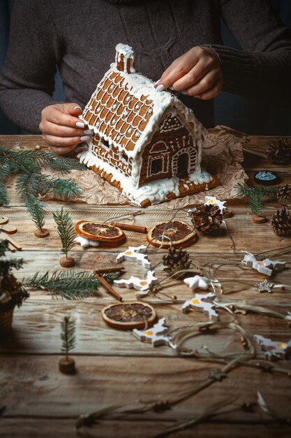 Young Female hands decorate the Christmas gingerbread house