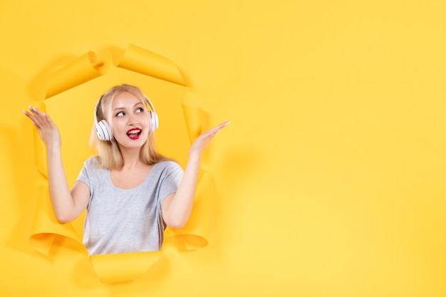 Young female in headphones on yellow background sound music audio