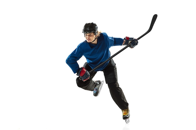 Young female hockey player with the stick on ice court and white background. Sportswoman wearing equipment and helmet training. Concept of sport, healthy lifestyle, motion, action, human emotions.