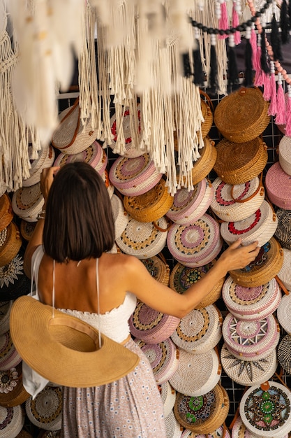 Young female is coming to local basketry shop for buying some exotic bags during her trip