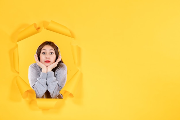 young female listening to music in headphones on a yellow background audio ultrasound sound