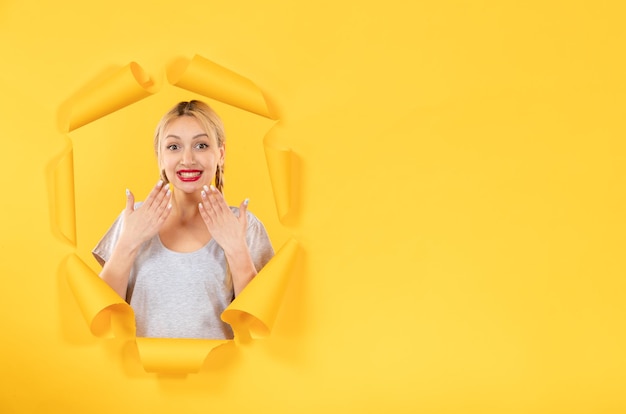 Young female looking from torn yellow paper background sale indoor window facial