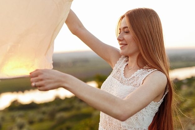 Young female making wish and launching paper sky lantern