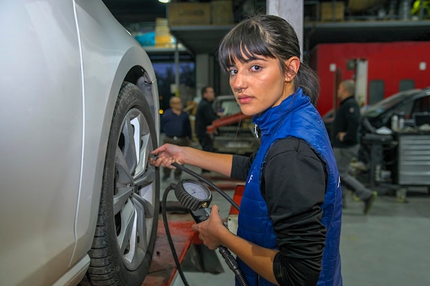 Young female mechanic checking the air pressure of a car's tires