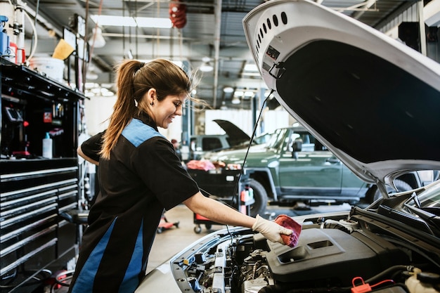 Photo young female mechanic wiping the engine oil dipstick