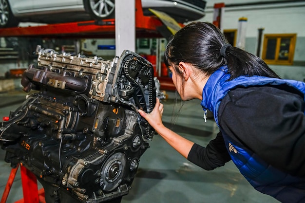 Young female mechanic working on the repair of a car engine