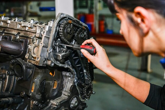 Young female mechanic working on the repair of a car engine