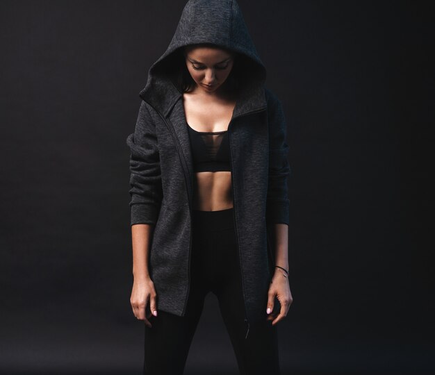 Photo young female model in sportswear standing on black