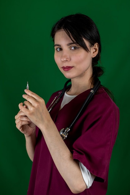 Young female nurse holds a syringe with a needle in her hand in medical clothes isolated